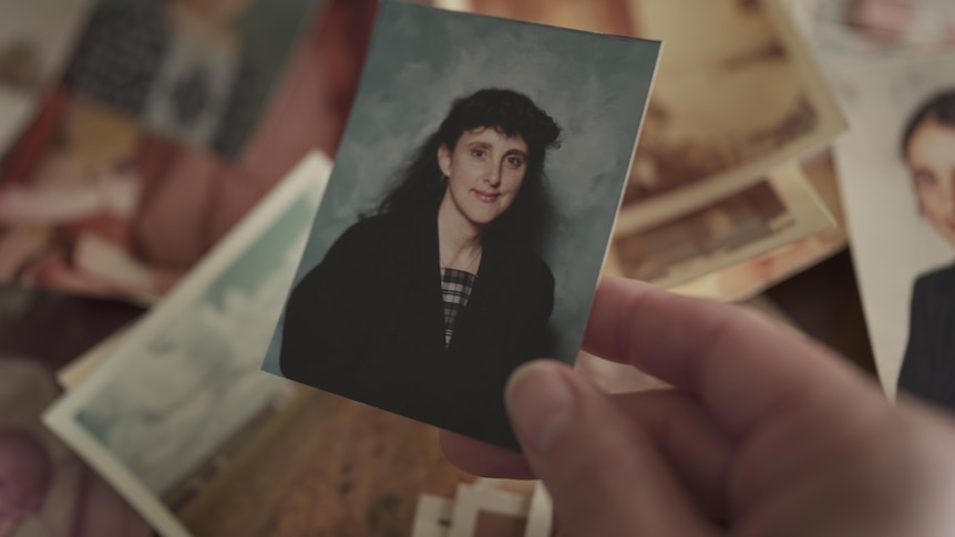 Woman holding up a small photo of Marion Barter.