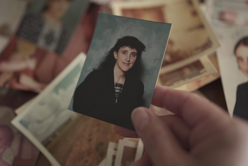 Woman holding up a small photo of Marion Barter.