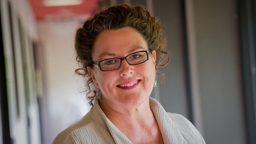 A dark-haired, bespectacled woman smiling.