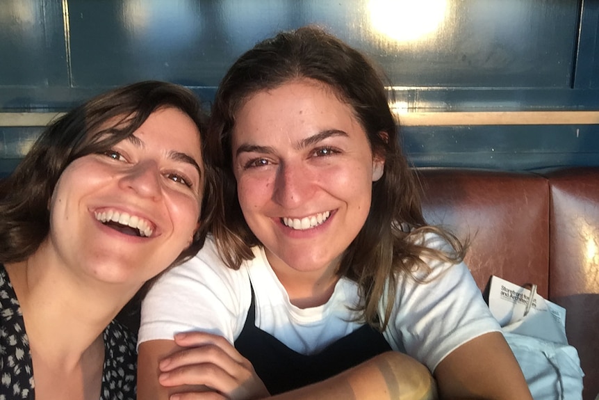 Twin sisters pose in a restaurant booth