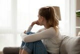 woman sitting on the couch curled up and looking away