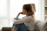 woman sitting on the couch curled up and looking away