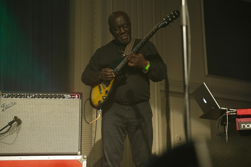 A man playing guitar on stage.