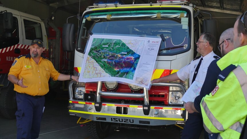 Crew use map attached to fire truck to explain the spread of the fire