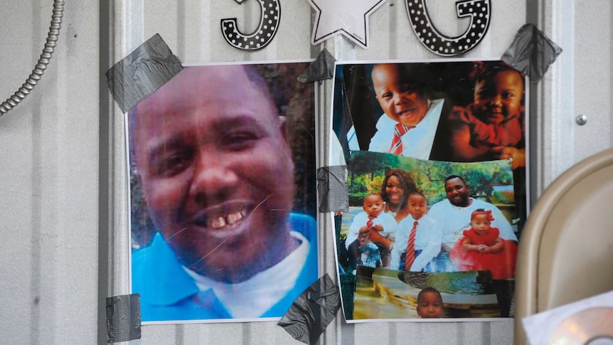 Photos of Alton Sterling are taped to the wall at a makeshift memorial outside the Triple S convenience store.