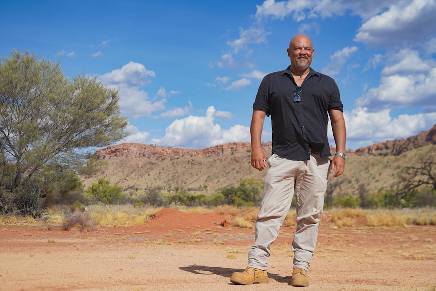 Aaron Campbell stands in front of a mountain range in Central Australia.