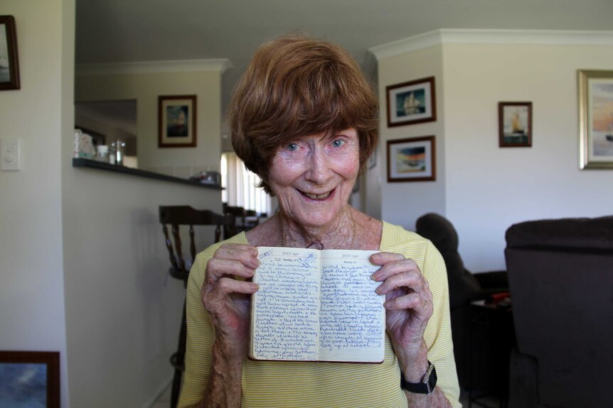 A woman holds an old diary.