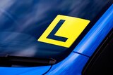 Close up of a L-plate on a blue car.