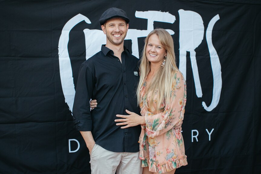 A man and a woman pose on a red carpet.