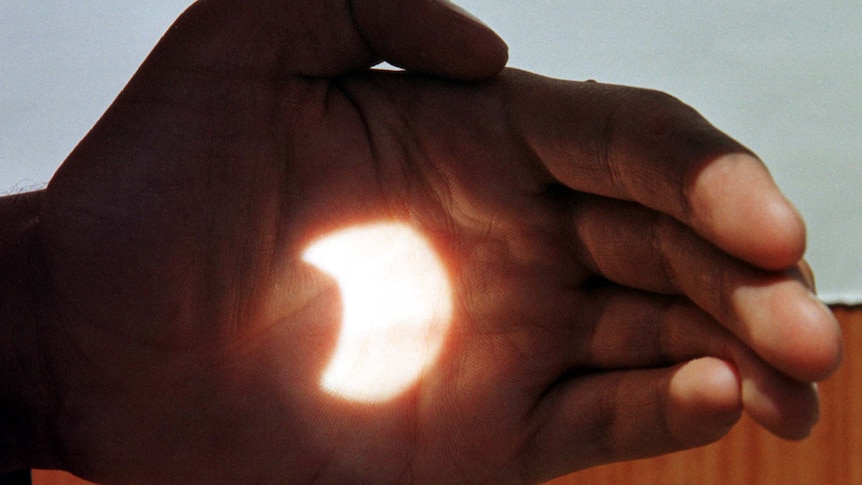  A partially-covered Sun is reflected on someone's hand