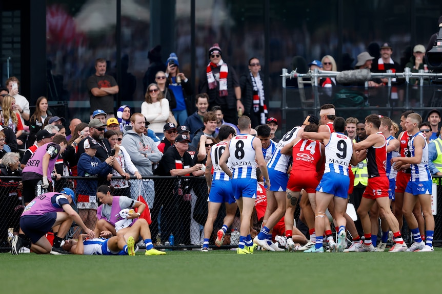 St Kilda and North Melbourne players scuffle as Jy Simpkin lies on the grass beside them during an AFL preseason game.