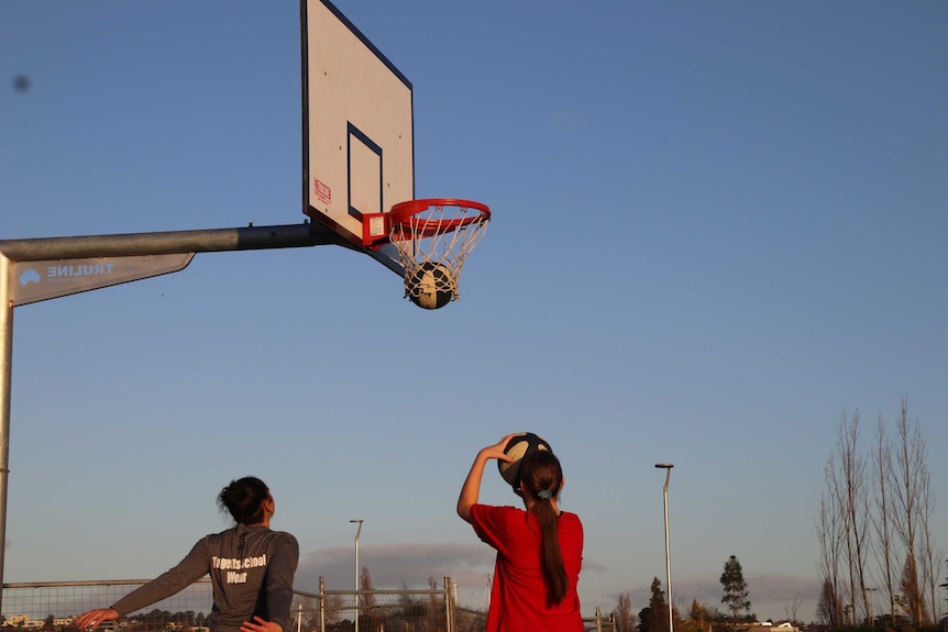 Basketball players shooting hoops outside