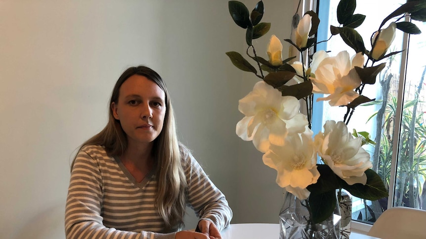 Woman at table stares into distance.