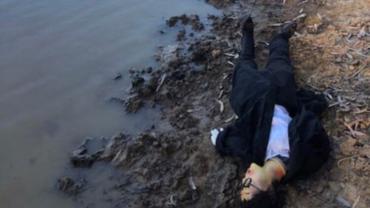 Human-like dummy lies on riverbank