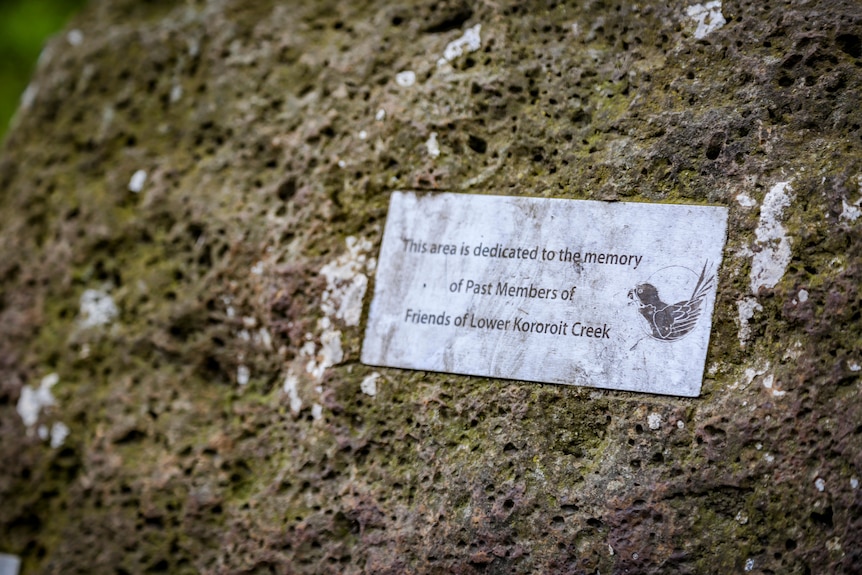A plaque on a mossy rock signifying that the area is dedicated to past members of the Friends of Lower Kororoit Creek group 