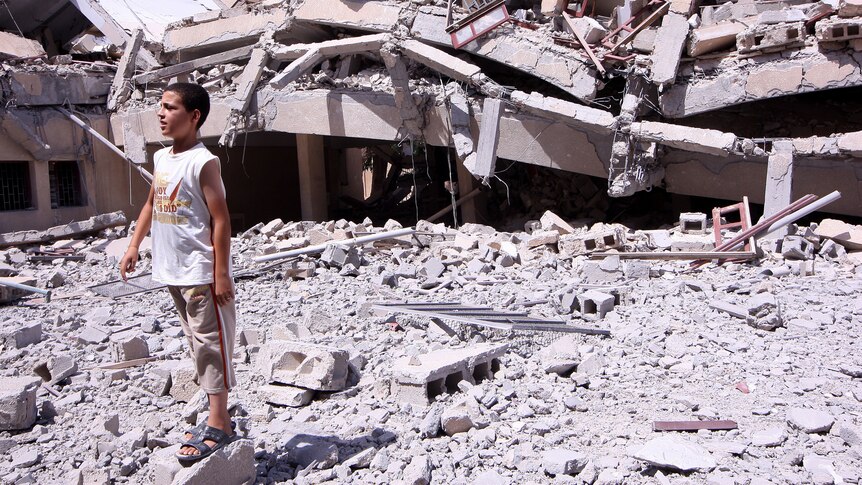 A Libyan boy stands amid the rubble outside the rubble of a school in Zliten.
