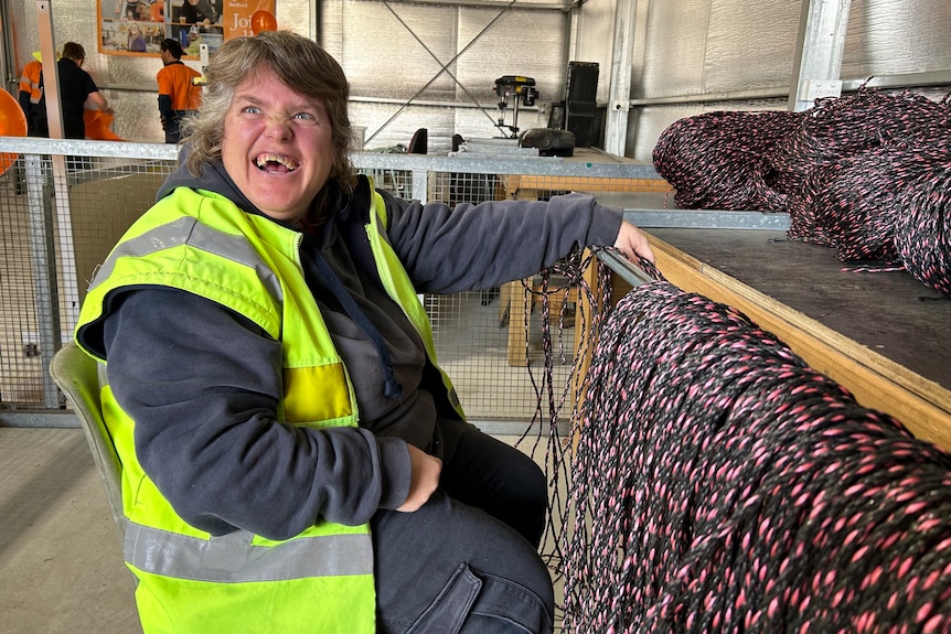 A woman sitting next to a table of ropes