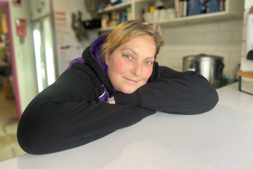 A woman in a black jumper leans on a bench