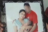 A framed picture of Ravneet Kaur cradling a newborn standing next to her husband. His face and the baby's face is blurred.