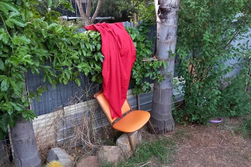 A chair and red sheet on a fence