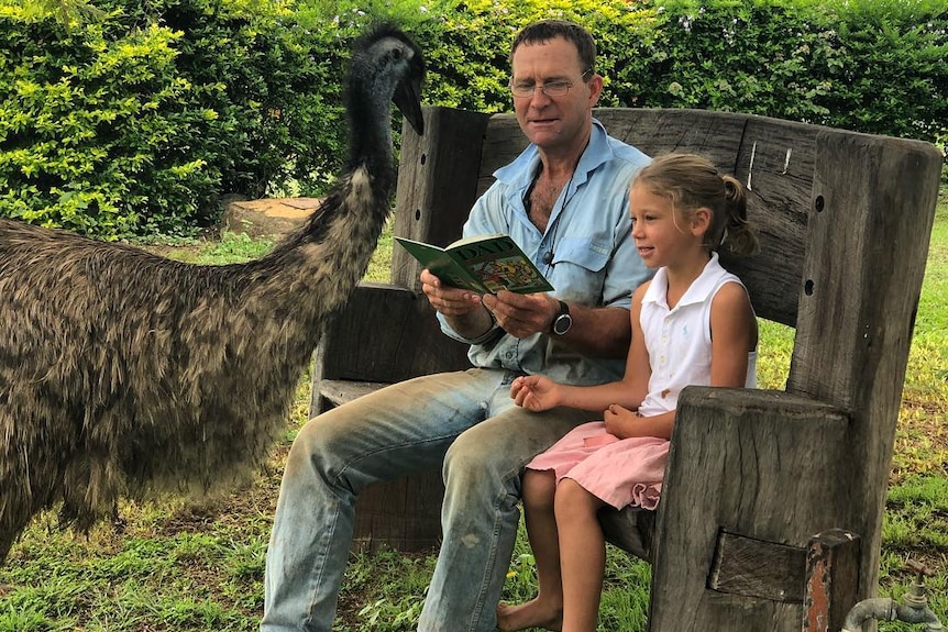 Fred the emu is looking over Rob and Eliza reading.