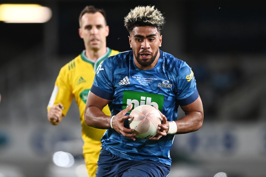 A Blues Super Rugby trans-Tasman player holds the ball in two hands.