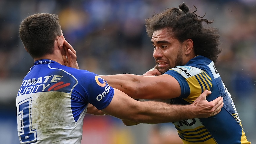 A Parramatta NRL player attempts to fend off a Canterbury opponent.