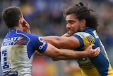 A Parramatta NRL player attempts to fend off a Canterbury opponent.
