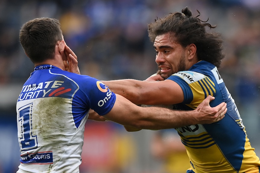 A Parramatta NRL player attempts to fend off a Canterbury opponent.