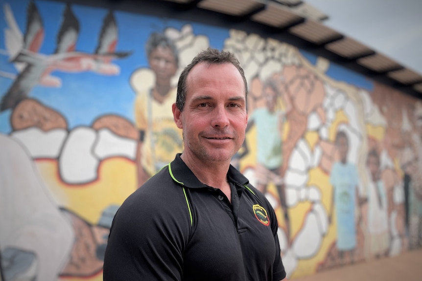 A man in front of a colourful wall