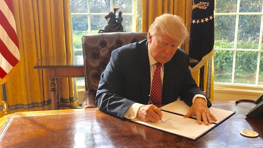 US President Donald Trump signs a revised executive order.