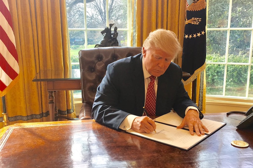 US President Donald Trump signs a revised executive order.