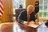 US President Donald Trump signs a revised executive order.
