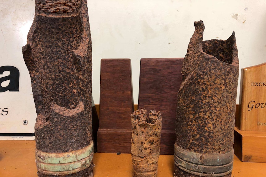 Rusted bomb shells on shelf.