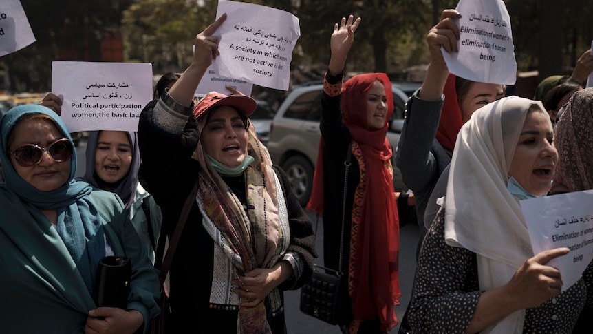 Women hold paper signs and protest in Kabul
