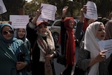 Women hold paper signs and protest in Kabul