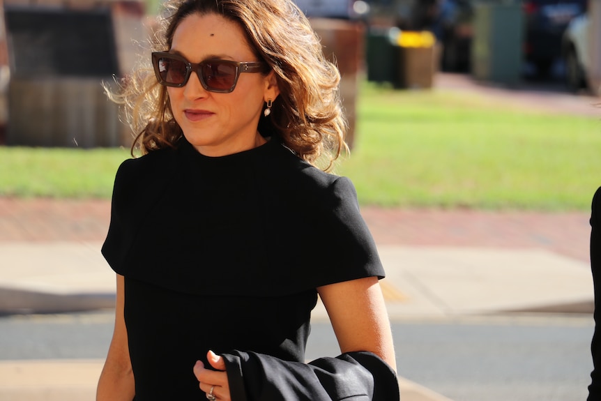 A woman wearing a black shirt with dark, curly hair walks into the Alice Springs Court.