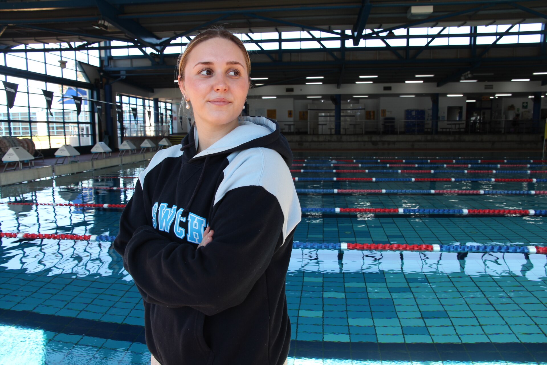 A young woman smiling in front of an indoor pool.
