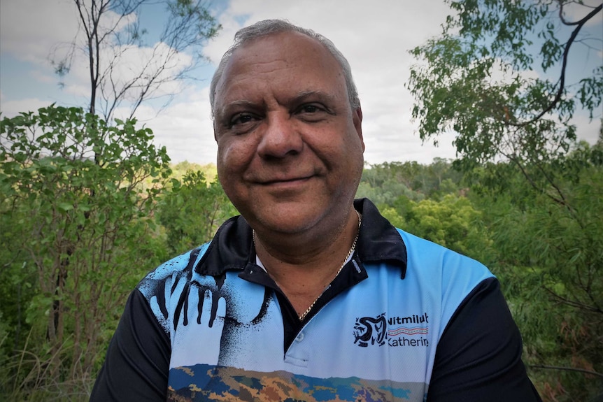 headshot of man looking at camera smiling wearing Nitmiluk Katherine shirt against a lush bush backdrop