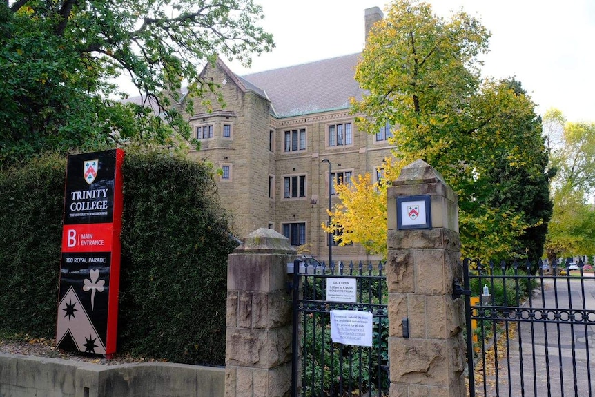 A historic-looking building with a sign on the front fence reading Trinity College.