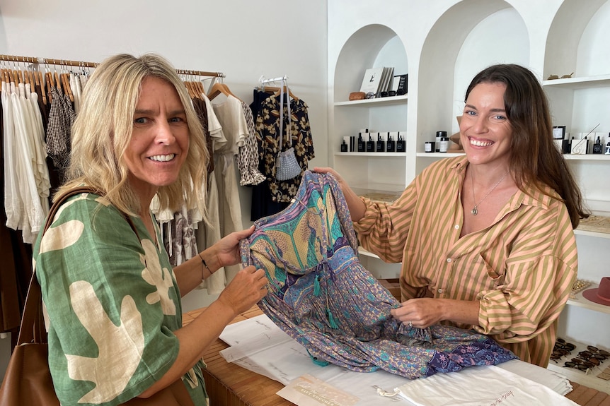 two women with clothing at a fashion store desk