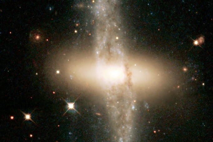 A bulging diffuse yellow disk is wrapped up by a bumpy ring of stars and dust