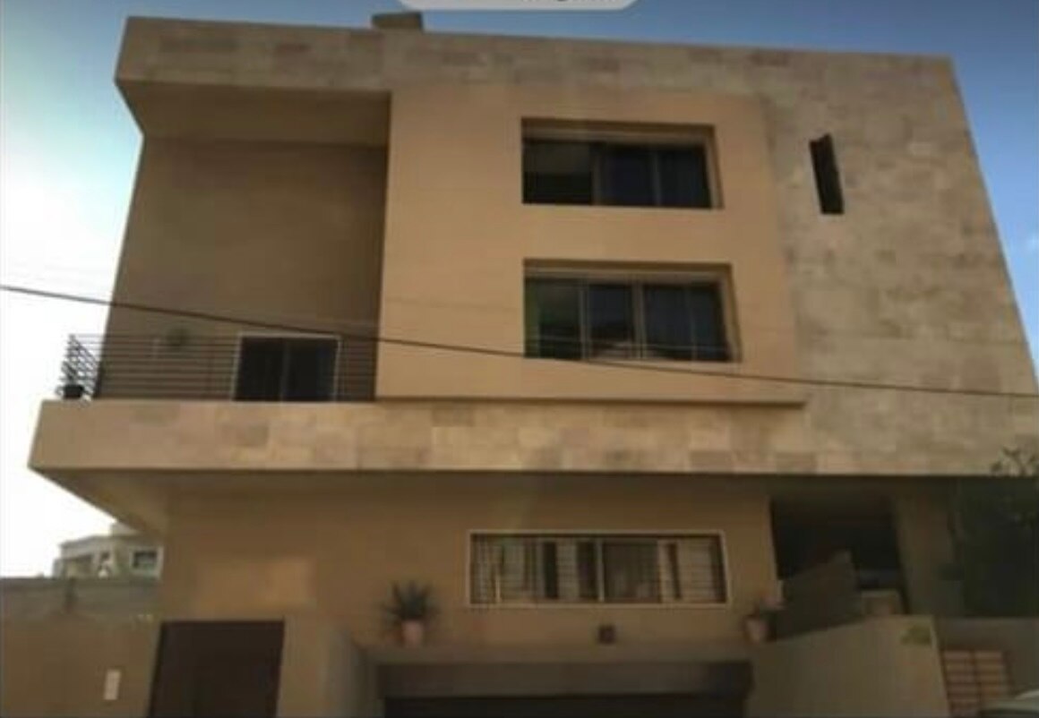 A tan coloured home with pot plants outside the front of it.