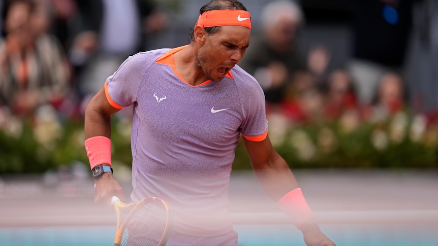 Spanish tennis star Rafael Nadal, in a purple shirt and orange headband, pumps his first after winning a point
