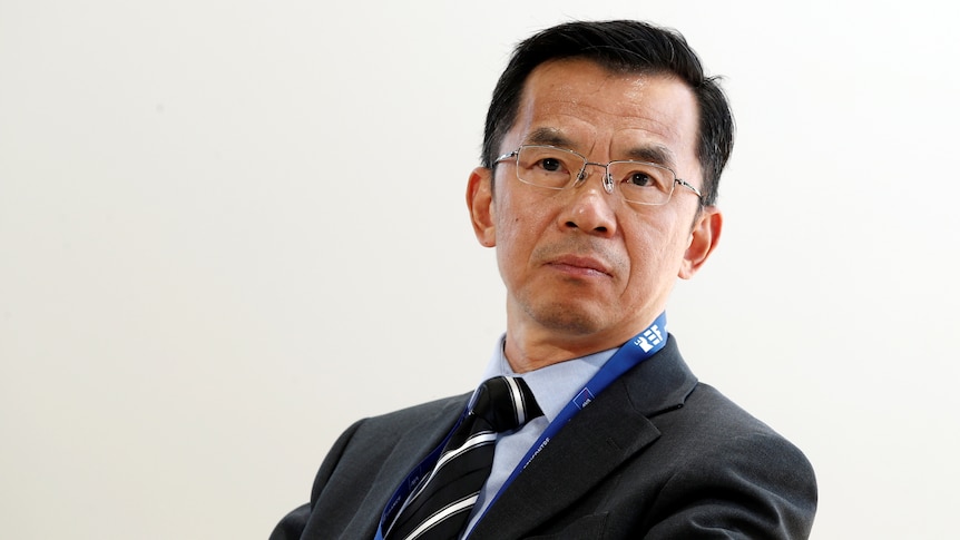 Chinese Ambassador in France Lu Shaye sits in front of a plain white wall.