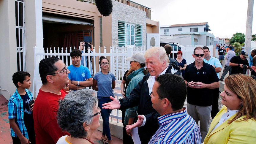 Donald Trump talks with local residents during a walking tour of areas damaged by Hurricane Maria.