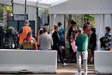 People wearing masks queue up for vaccination at the NSW Vaccine Centre at Sydney Olympic Park.