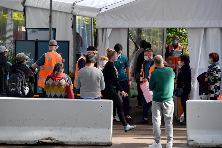 戴口罩的人们在悉尼奥林匹克公园的新州疫苗接种中心排队接种疫苗。