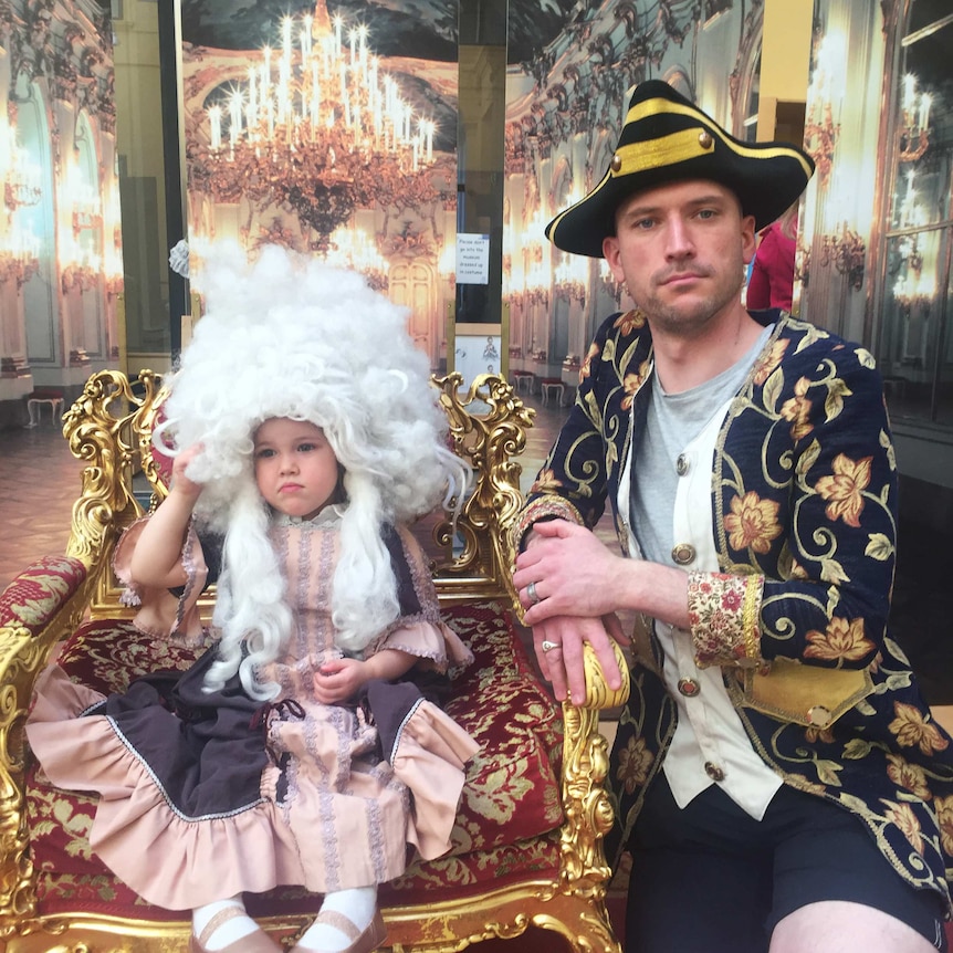 Photo of Regina's husband Leigh with their daughter, who are both in costume and sitting in a museum throne in Vienna