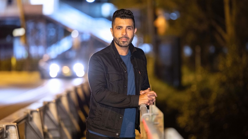 Patrick Abboud standing on the street at night with car headlights in the background.